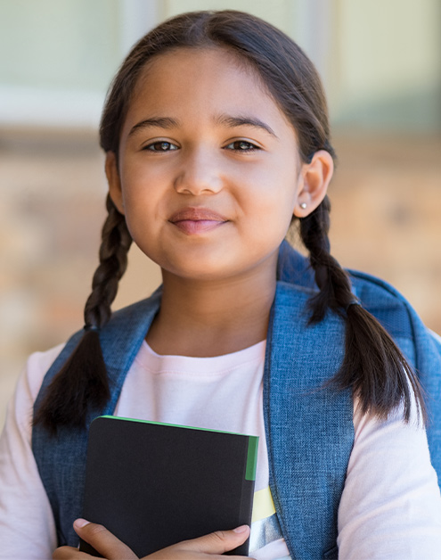 Girl with brown hair and a blue backpack holding a notebook